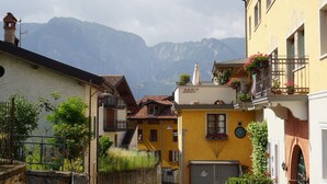 A building with a balcony, a staircase, and a mountain in the background.