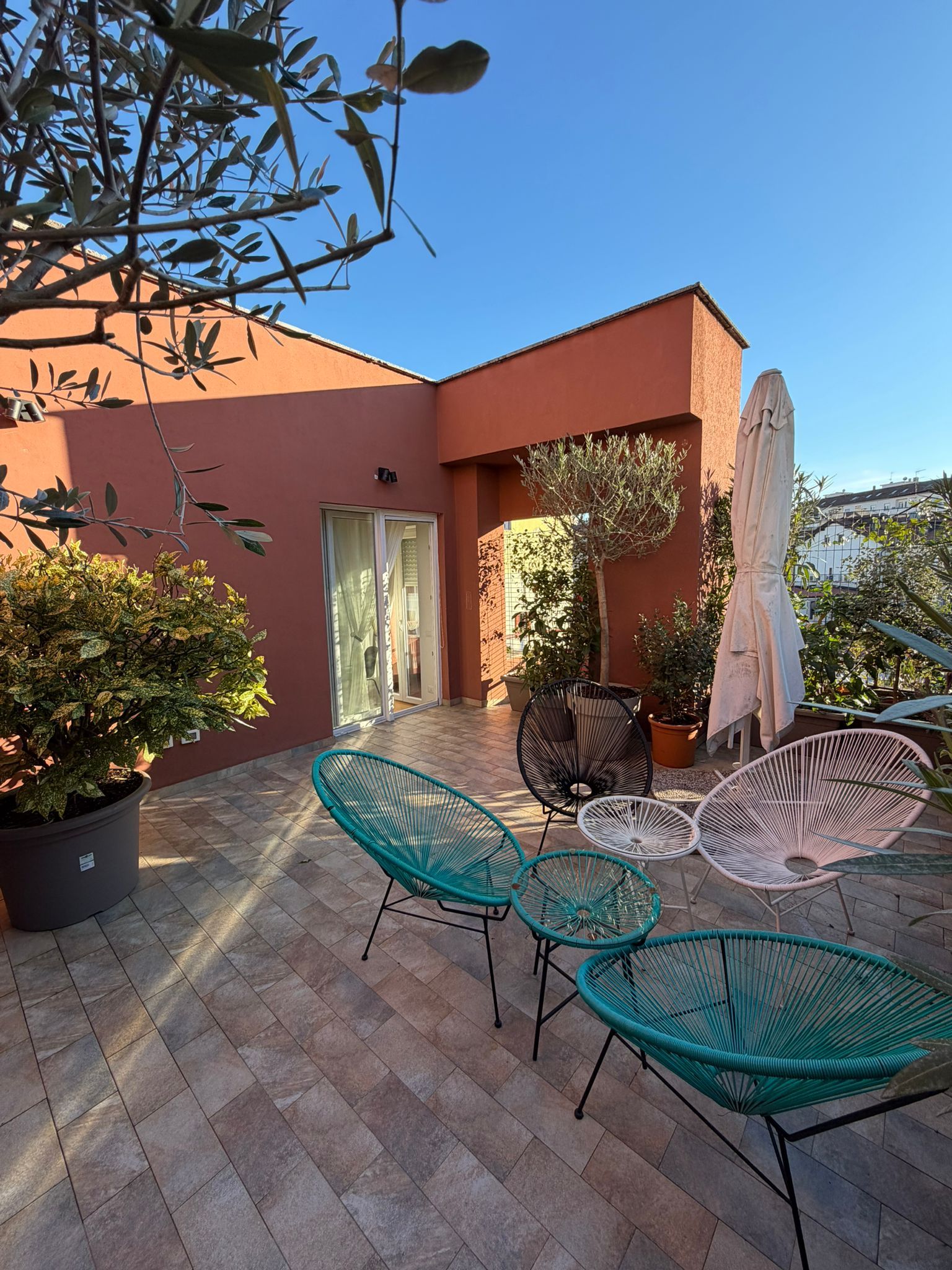 Une terrasse extérieure avec un sol carrelé, une porte et un espace détente comprenant des chaises et une table.
