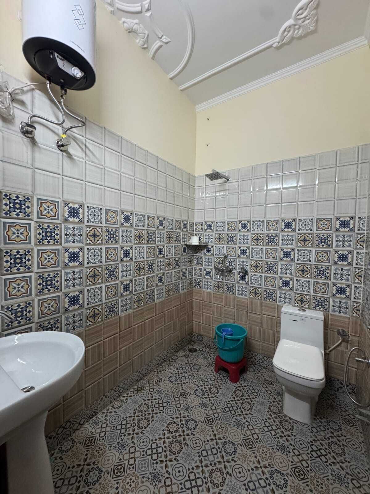 A bathroom with patterned tiles, a sink, a toilet, and a shower head.