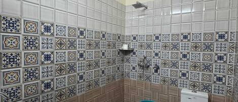 A bathroom with patterned tiles, a sink, a toilet, and a shower head.