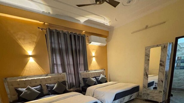 A hotel room with two beds, a ceiling fan, a wall-mounted air conditioner, and a marble-patterned floor.