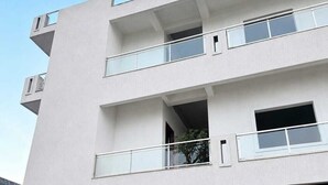 A multi-story building with balconies, a red shuttered entrance, and signage for 'Bhagirath Residency.'