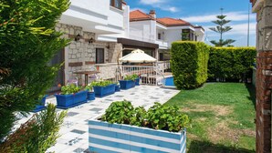 A courtyard with potted plants, a white building with a tiled roof, and a well-maintained lawn. - Alatrio Hotel Alaçatı (Cesme)