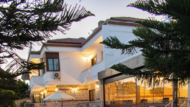 A swimming pool with a wooden deck, a white building with a balcony, and a staircase. - Alatrio Hotel Alaçatı (Cesme)