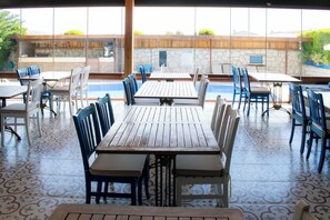 A patio area with tables and chairs, a pool, and a stone wall. - Alatrio Hotel Alaçatı (Cesme)