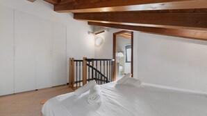 A bedroom with a wooden ceiling, a bed with white linens, a wooden railing, and a white wardrobe. - Vivienne In Front Of Pool Holiday Home with Shared Pool, Wi-Fi & Air Conditioning (Desenzano del Garda)