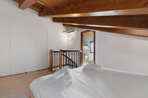 A bedroom with a wooden ceiling, a bed with white linens, a wooden railing, and a white wardrobe. - Vivienne In Front Of Pool Holiday Home with Shared Pool, Wi-Fi & Air Conditioning (Desenzano del Garda)