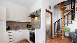 A modern kitchen with white cabinets, a stone backsplash, and a built-in oven. - Vivienne In Front Of Pool Holiday Home with Shared Pool, Wi-Fi & Air Conditioning (Desenzano del Garda)