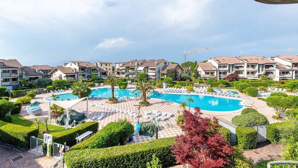 A resort with a central swimming pool, multiple lounge areas, and a well-maintained garden. - Vivienne In Front Of Pool Holiday Home with Shared Pool, Wi-Fi & Air Conditioning (Desenzano del Garda)