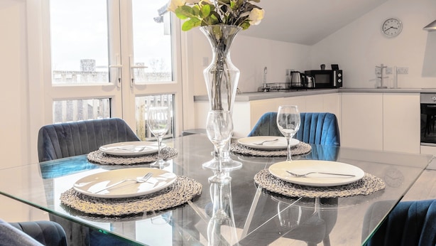 A dining table set with plates, cutlery, and a vase with flowers. - Rooftop - Sleeps 2 - Central - Paid Parking - Wifi (Maidstone)