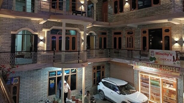 A multi-story building with a restaurant named 'Minchy's' and a sign for 'Fruit Wine House.' - Narayan Guest House Kasol (Kasol)