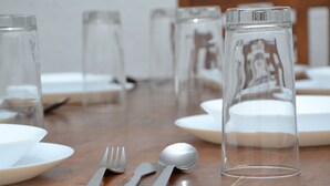 A dining table with clear glassware, white plates, and cutlery.