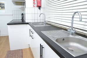 A kitchen with two sinks, white cabinets, and a black countertop. - Manchester Ashton Suites (Ashton-under-Lyne)