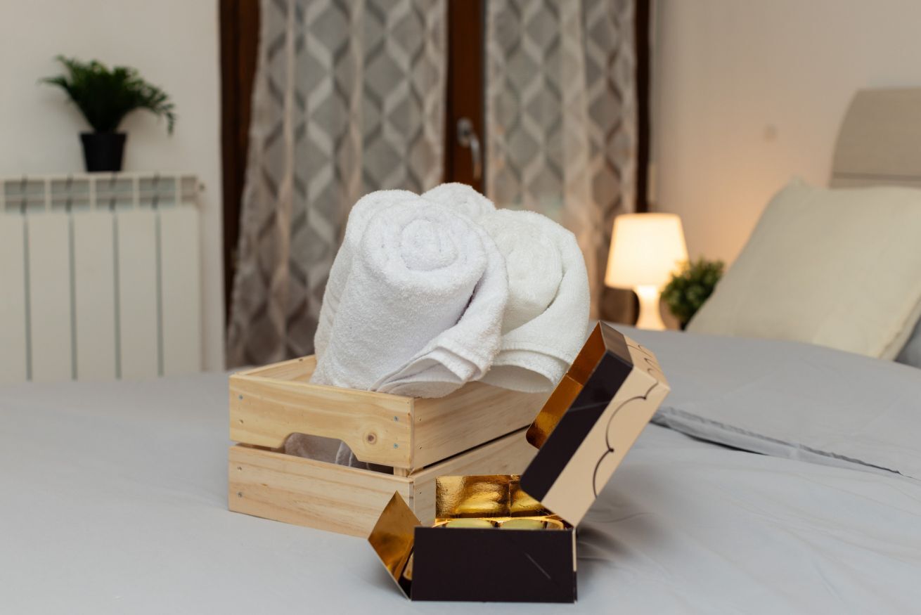 Una caja de madera con una toalla encima y una caja más pequeña con interior dorado sobre una cama.
