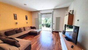 Una sala de estar con un sofá seccional, un televisor de pantalla plana y un ventanal corredizo que da a un patio.