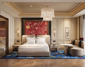 A hotel room with a large bed, a chandelier, a red floral wall, and a sofa.