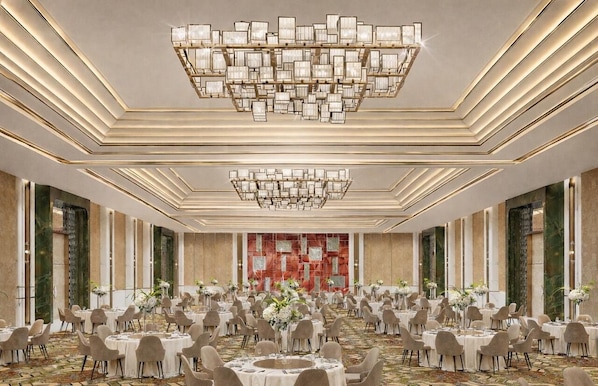 A spacious banquet hall with round tables, a large chandelier, and a patterned carpet. - Altara Indore (Indore)