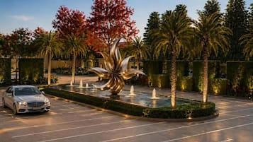 A parking lot with a fountain and palm trees.