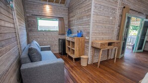 Una habitación con un sofá gris, estantes de madera, una mesita y una ventana con vistas.