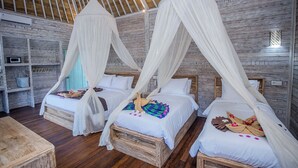 Una habitación con tres camas, cada una con dosel, suelo de madera y un diseño rústico en la pared.