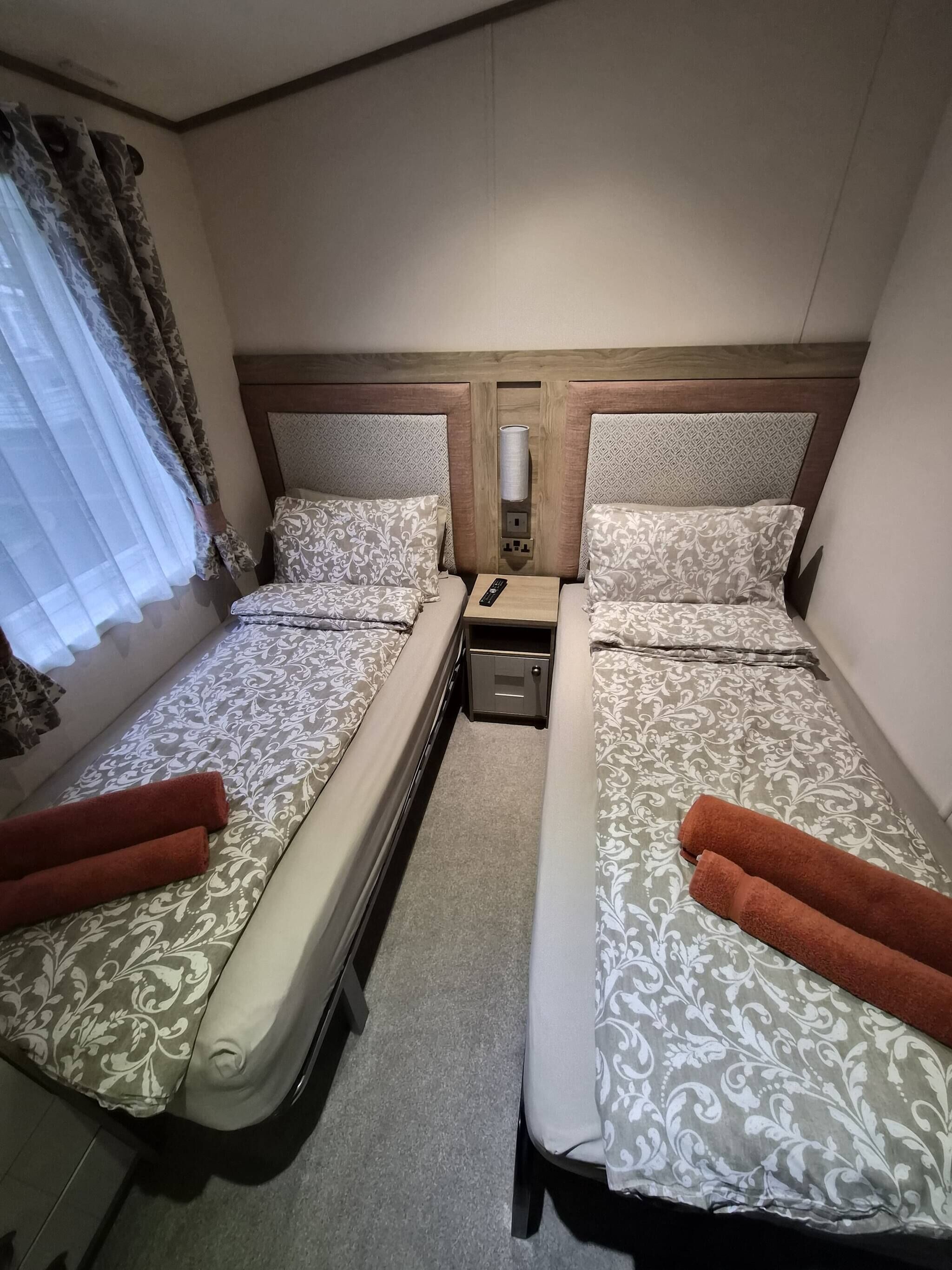 Une chambre d’hôtel avec deux lits, chacun agrémenté de draps à motifs et doté d’une télécommande sur la table de chevet.