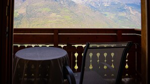 Une terrasse en bois avec une table et une chaise, offrant une vue sur un paysage montagneux.