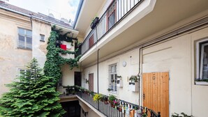 A narrow urban courtyard with a wooden door, potted plants, and a staircase leading to an upper level. - Riverside 2BR Apartment Next to the National Theatre by EasyBNB Premium (Prague)