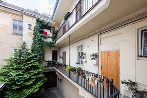 A narrow urban courtyard with a wooden door, potted plants, and a staircase leading to an upper level. - Riverside 2BR Apartment Next to the National Theatre by EasyBNB Premium (Prague)