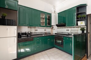 A kitchen with green cabinets, a white refrigerator, a stove, and a microwave. - Riverside 2BR Apartment Next to the National Theatre by EasyBNB Premium (Prague)