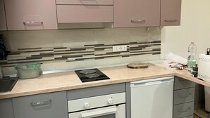 Une cuisine au design moderne, dotée d’un plan de travail, d’un four encastré et d’un crédence avec un motif à rayures.