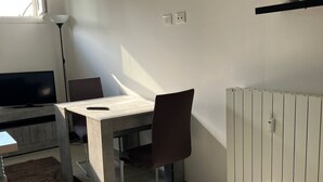 Une pièce moderne comprenant une table à manger, une chaise, un téléviseur, un radiateur et une horloge murale.