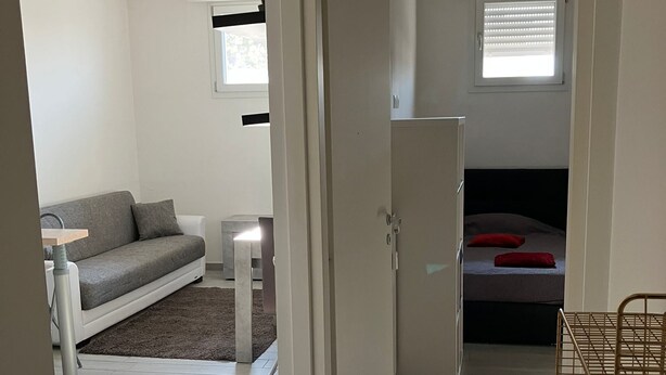 Une pièce de taille modeste, comprenant un canapé, un lit, une petite table et un radiateur.