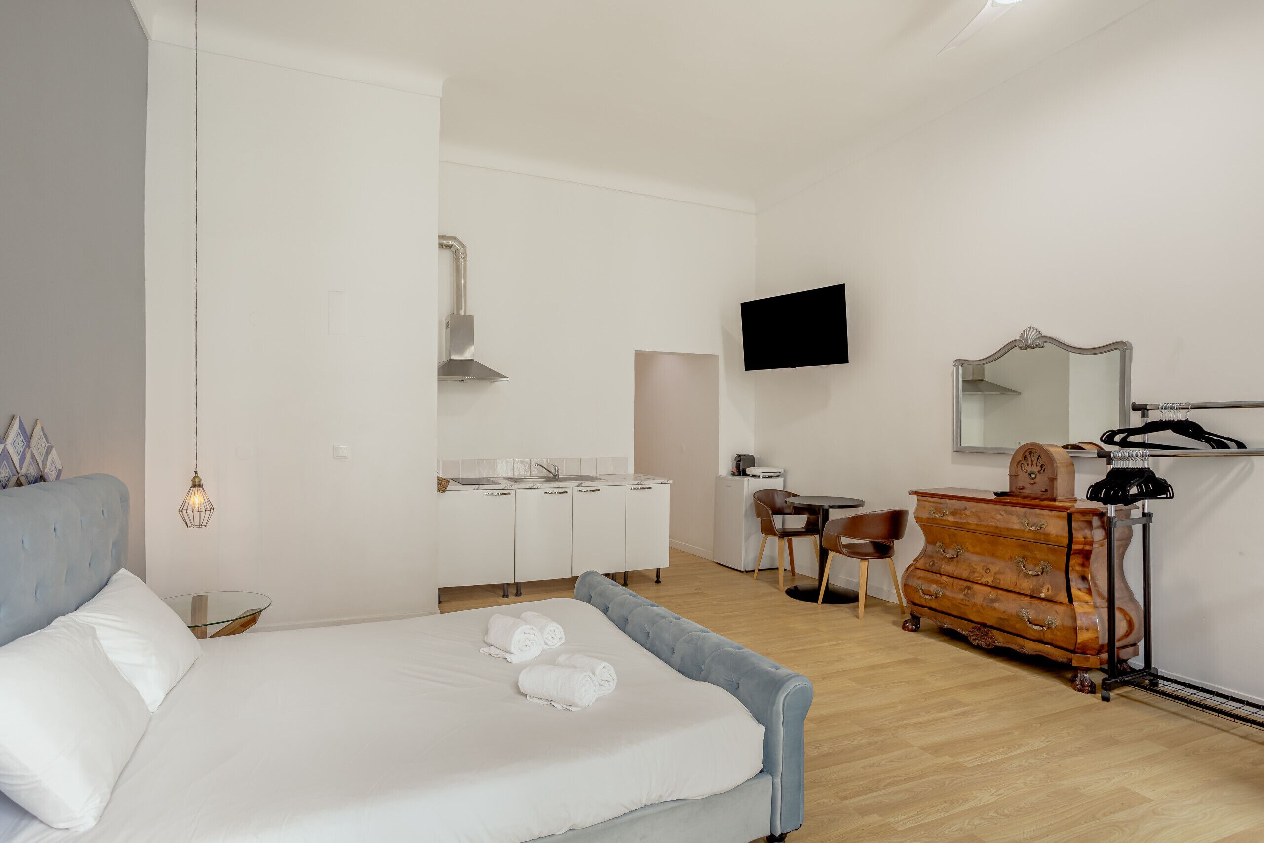 A bedroom with a bed, a desk, a chair, a dresser, and a television.