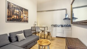 Ein modernes Wohnzimmer mit grauem Sofa, einem Holztisch und einem Essbereich mit weißem Tisch und Stühlen.