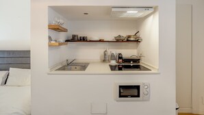 Eine kleine Küche mit integriertem Mikrowellenherd, einer Kaffeemaschine und einem Toaster.