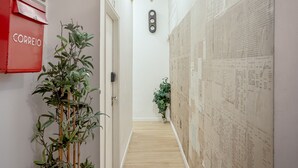 Ein Flur mit einem roten Briefkasten mit der Aufschrift 'CORREIO', einer Bambuspflanze und einer Wand mit einer großen, detaillierten Karte.