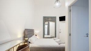 A bedroom with a bed, bedside table, chairs, a mirror, and a door. - Boavista 130 Studios I by Homing (Lisbon)