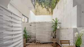 A courtyard with a white fence, wooden benches, and potted plants. - Boavista 130 Studios I by Homing (Lisbon)