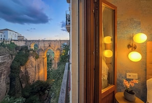 A room with a view of a historic bridge, a wooden door, and a wall-mounted light fixture. - Las Vistas II Residence · Stunning Gorge & Bridge Views (Ronda)