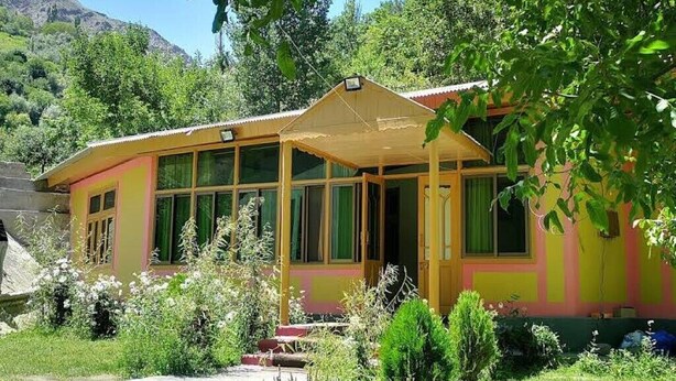 A single-story building with a porch, large windows, and a mountain backdrop.