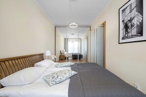 Ein Schlafzimmer mit Bett, Kissen, Nachttisch, Lampe und einem gerahmten Kunstwerk an der Wand.