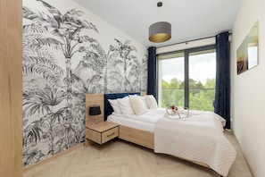 Una camera da letto con un letto, un comodino, un murale, una finestra con tende e un lampadario.