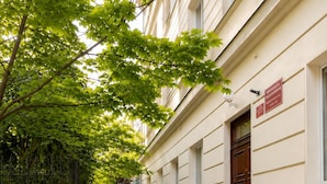 A building with a staircase leading to a door, surrounded by greenery and a paved area. - Lumina Apart near Museum Fryderyk Chopin (Warsaw)