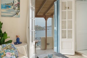 A room with a view of the sea, a painting on the wall, and a table with a vase. - Melina's sunset – Cozy flat with 2 rooms, 2 baths, and bay views in Myrties (Kalymnos)