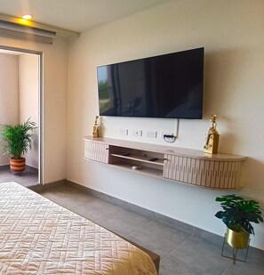Ein modernes Schlafzimmer mit einem großen Bett, einem an der Wand montierten Fernseher und integrierten Stauraumlösungen.