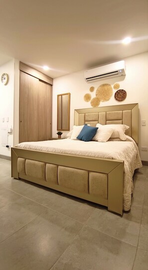 A bedroom with a bed, a wooden wardrobe, a wall-mounted air conditioner, and a clock on the wall. - Luxury Apartment Suite With Ocean Views and Swimming Pools! (Santa Marta)