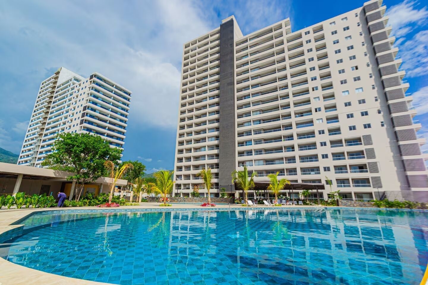 Une piscine dotée d’une plage carrelée, entourée de grands immeubles d’habitation avec des balcons.