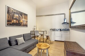 Ein modernes Wohnzimmer mit grauem Sofa, einem Holztisch und einem Essbereich mit weißem Tisch und Stühlen.