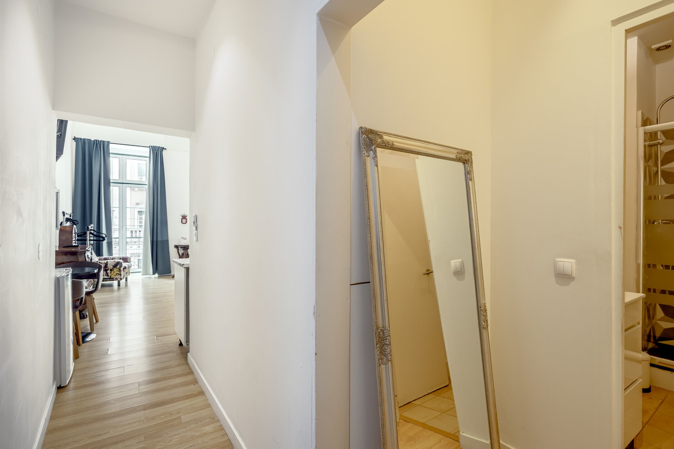 A hallway with a mirror, a door, and a staircase.