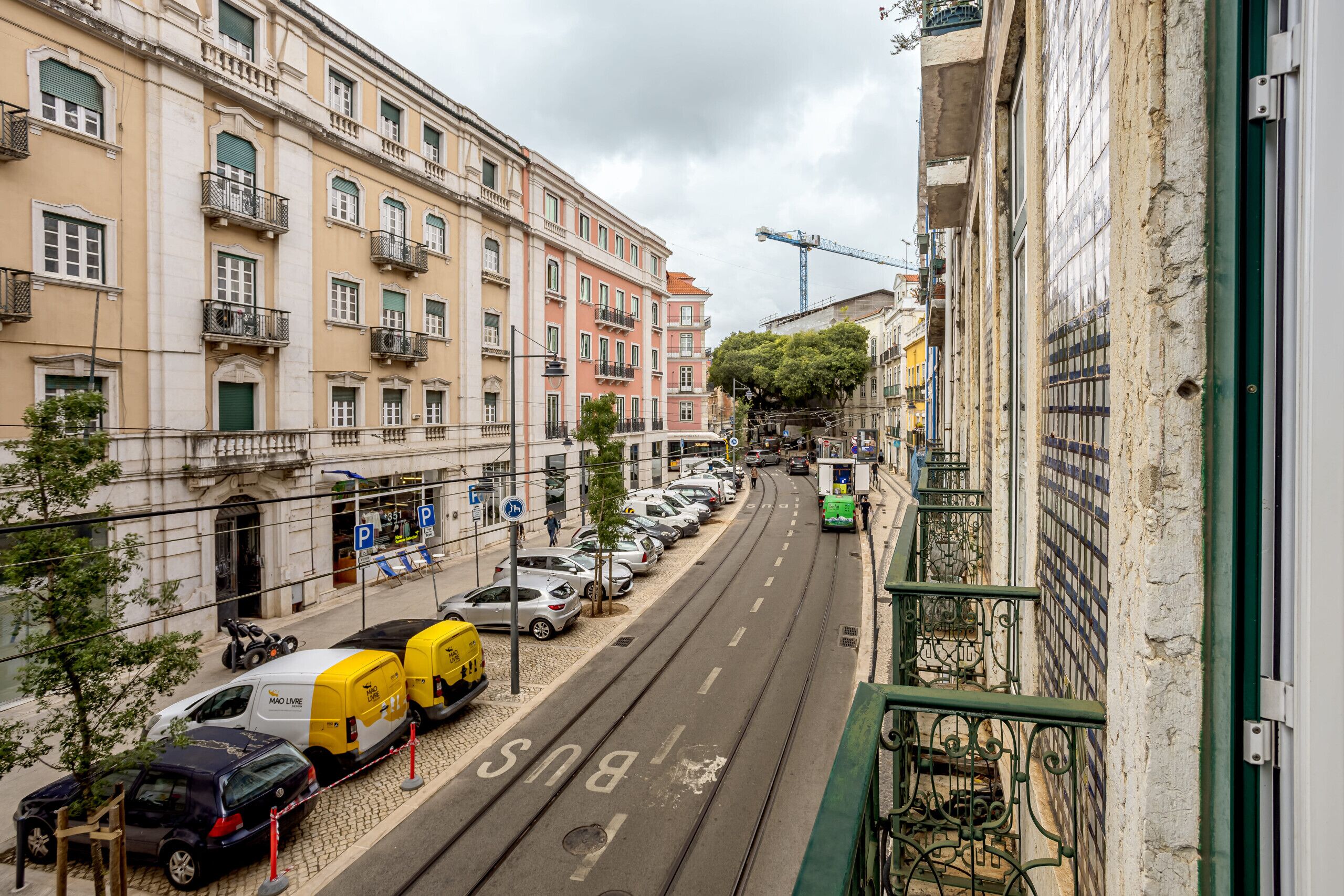 Une rue bordée de voitures garées et traversée par une ligne de tramway.